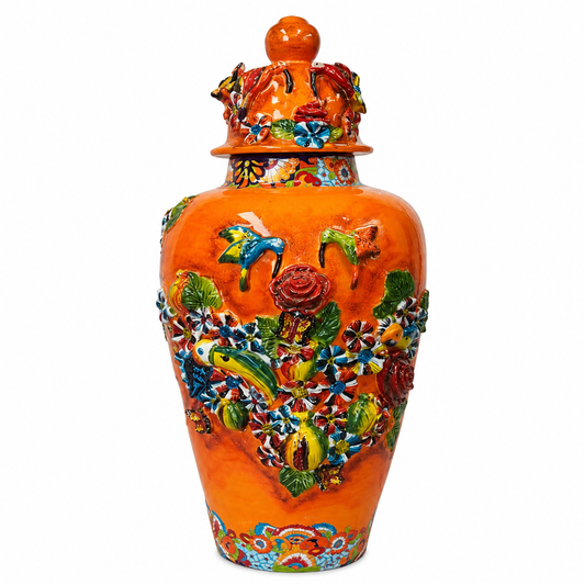An orange glazed ceramic lidded jar decorated with colorful raised floral and bird motifs, shown against a plain white background.